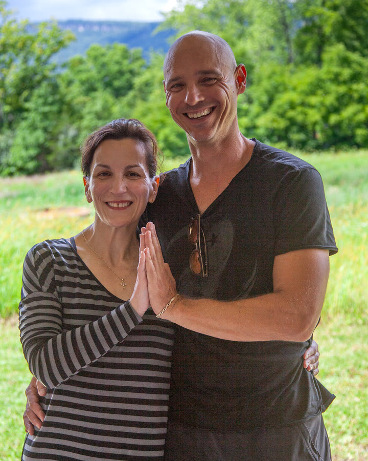 Erica Tortorella and Wayne Marino standing together outdoors in a green field, the Shawangunk Ridge behind them.